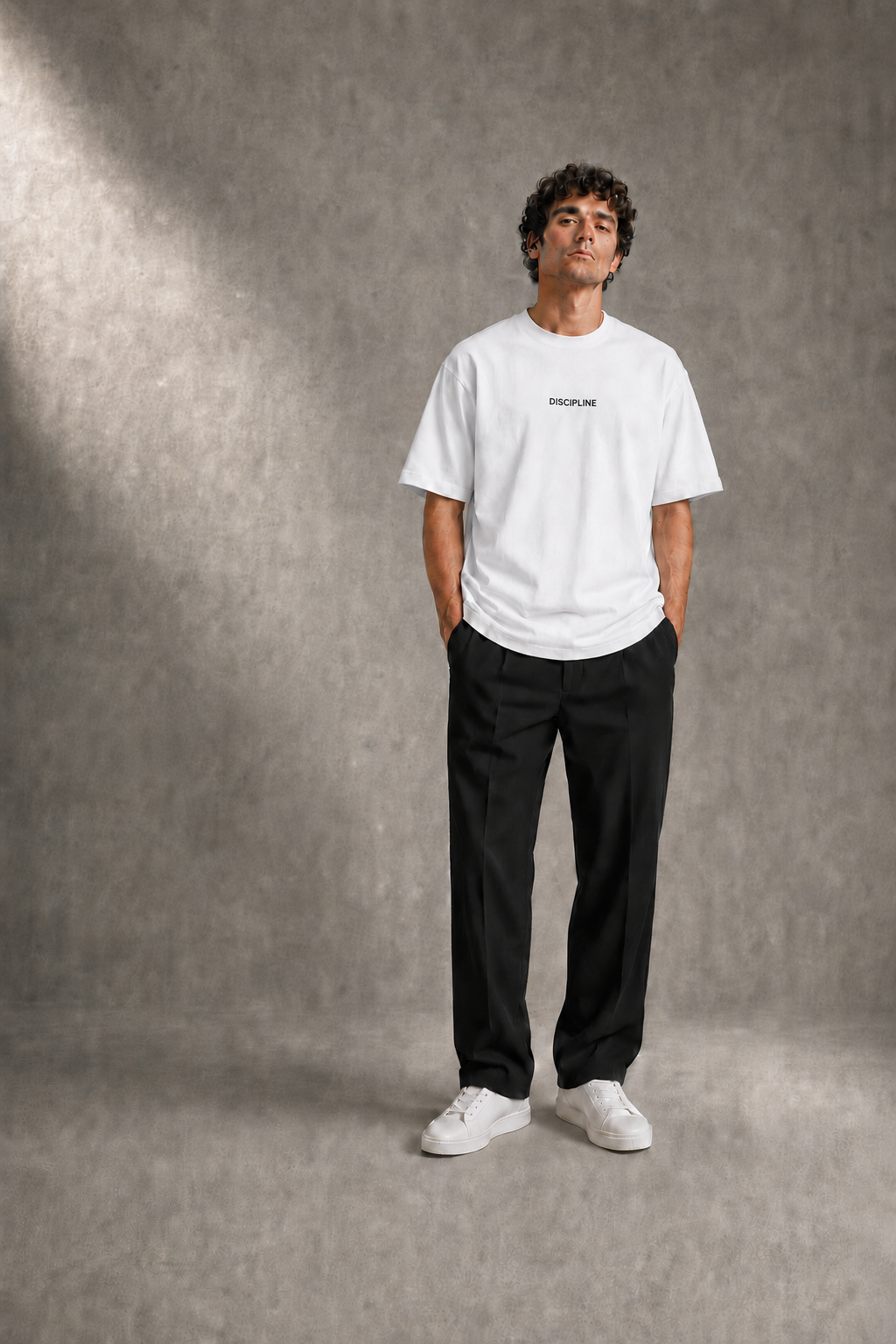 Luc wearing the DISCIPLINE tee in white against a concrete studio wall